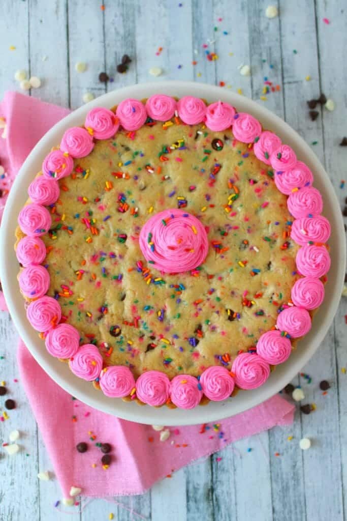 This Funfetti Giant Chocolate Chip Cookie Cake has party written all over it! Make with lots of rainbow sprinkles, white and semi-sweet chocolate chips and topped with a delicious buttercream frosting, this giant cookie is perfect for a birthday party or celebration!