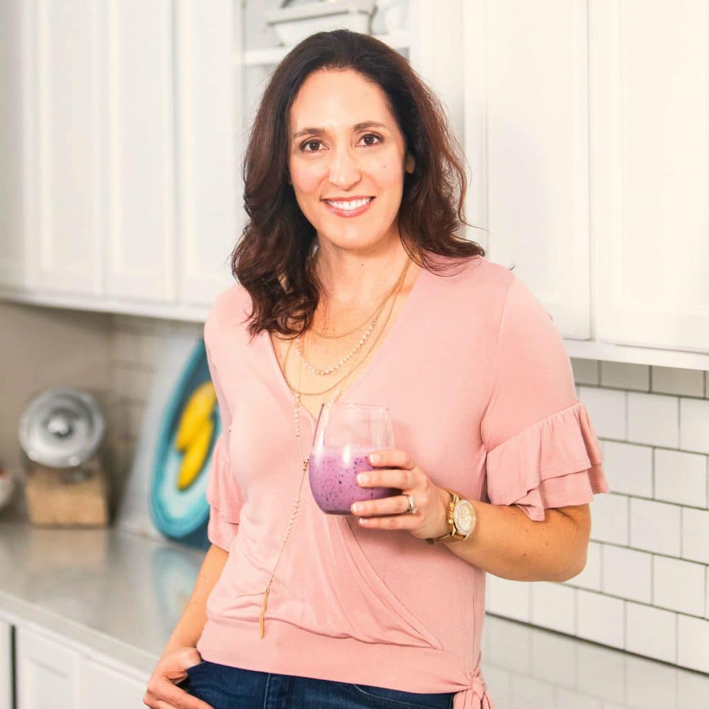 Photo of Erin holding a smoothie in a white kitchen.