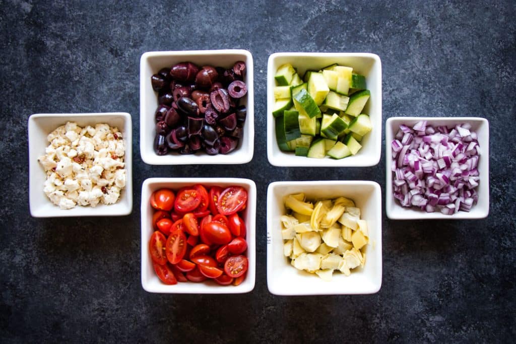 Greek tortellini salad ingredients in small bowls.