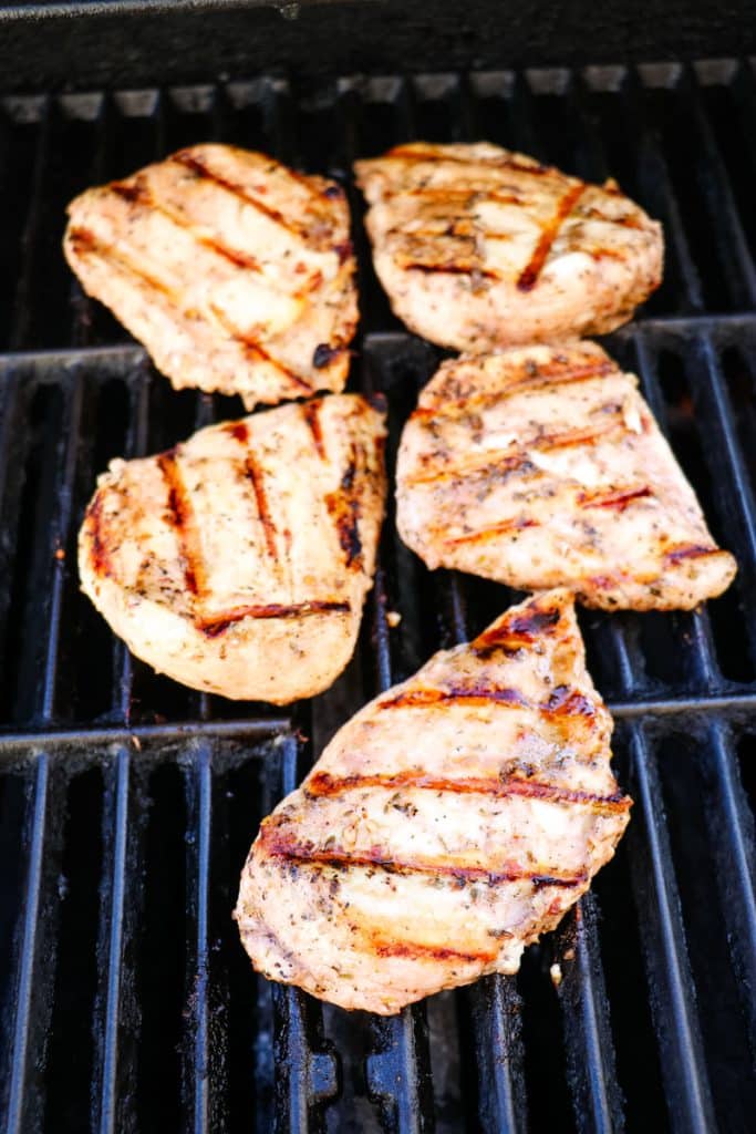 Italian marinated chicken breasts on the grill being cooked.