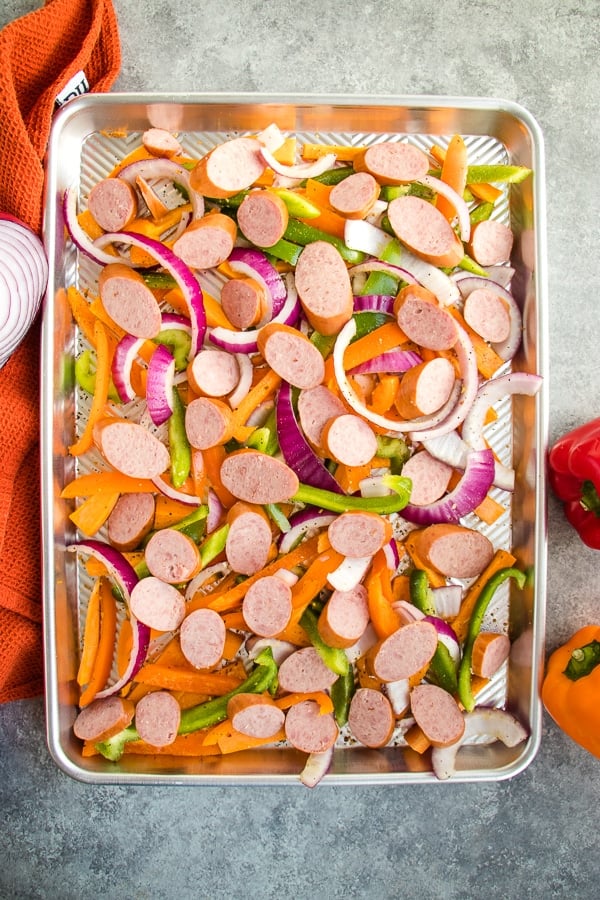 Could you use an easy weeknight dinner idea? This delicious baked sausage and peppers recipe is super easy and completely delicious! The perfect sheet pan recipe for a busy night, this dinner idea is done in under 30 minutes.