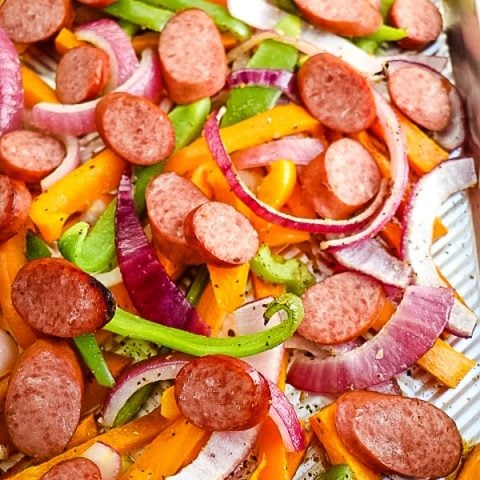 Could you use an easy weeknight dinner idea? This delicious baked sausage and peppers recipe is super easy and completely delicious! The perfect sheet pan recipe for a busy night, this dinner idea is done in under 30 minutes.