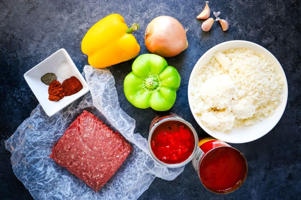 Ingredients needed to make unstuffed peppers, including ground beef, cauliflower rice, bell peppers and onion.