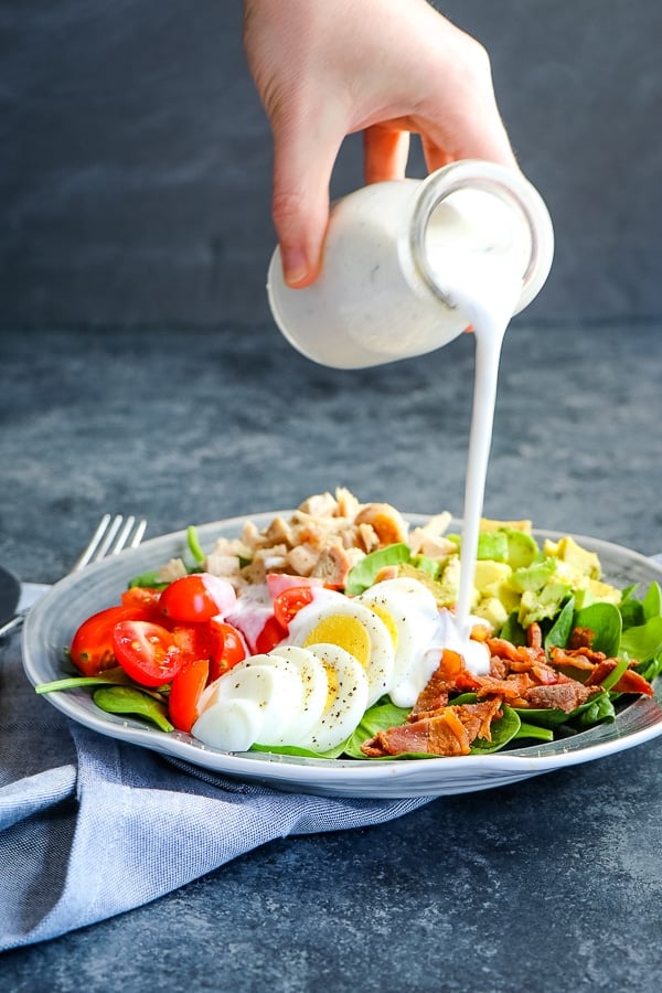 healthy Greek yogurt ranch dressing being poured over salad.