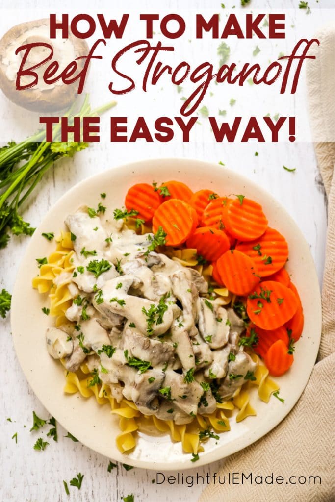 Classic beef stroganoff on top of curly egg noodles and sliced carrots on the side, all topped with chopped green parsley.