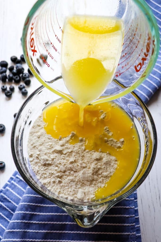 Melted butter being poured into a cake mix in a mixing bowl.