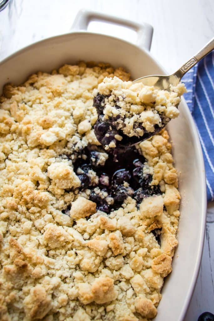 Baked cake mix blueberry cobbler with spoon taking out a scoop.