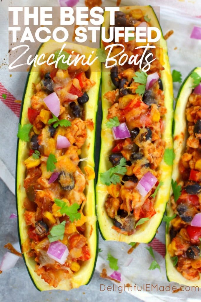 Two ground turkey taco stuffed zucchini boats, garnished with melted cheese and diced red onions.