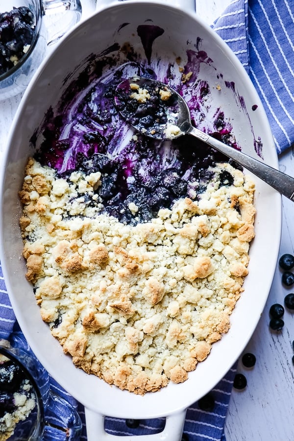 Close up image of blueberry cobbler with cake mix topping. Spoon is on the side.