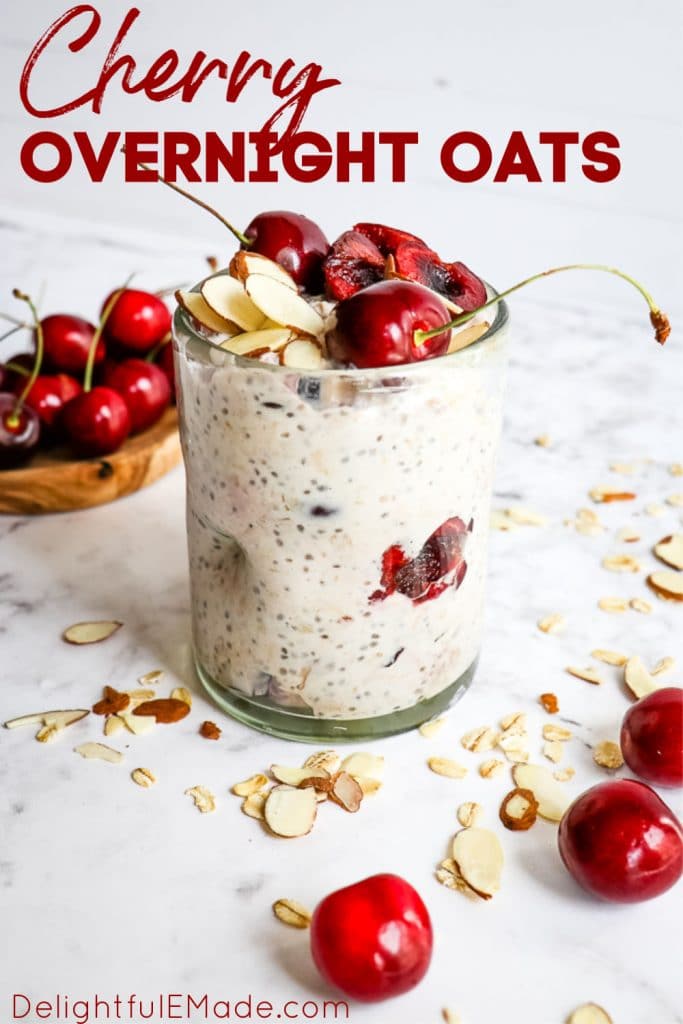 Clear jar of overnight oatmeal with fresh cherries on top and sliced almonds sprinkled over top.