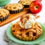 Apple pie tarts topped with ice cream, individual apple pies in background.