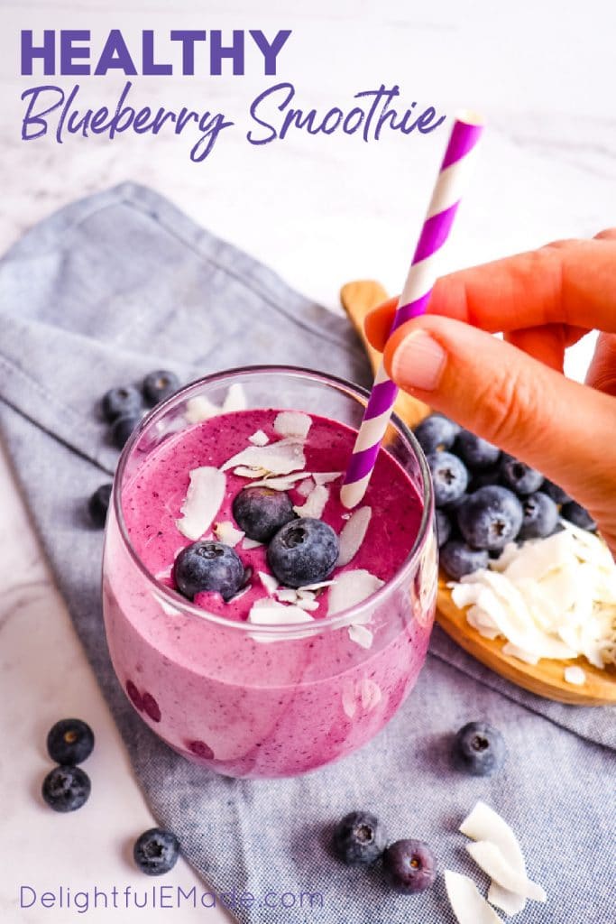 Healthy blueberry smoothie in a glass with paper straw.