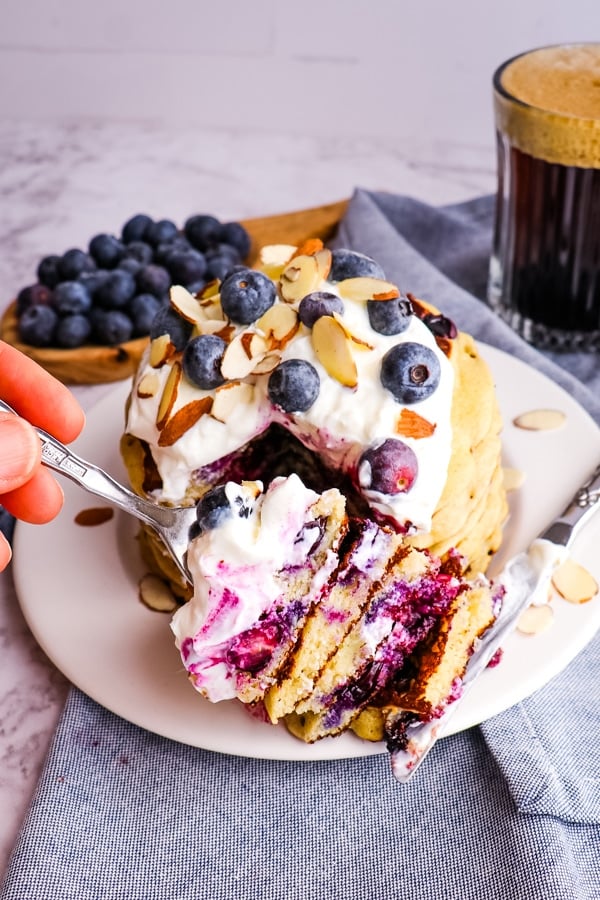 Stack of blueberry oatmeal pancakes topped with yogurt and blueberries.