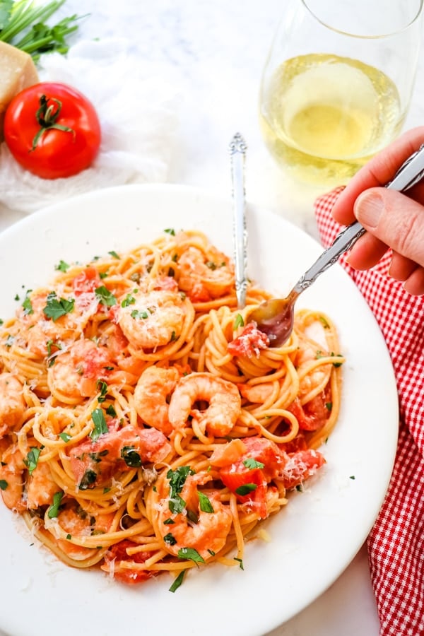 Shrimp rose pasta, plated with fork in pasta and glass of wine.