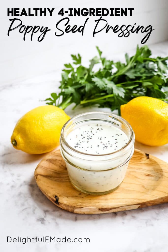 Creamy poppy seed dressing in small mason jar with lemons and parsley.
