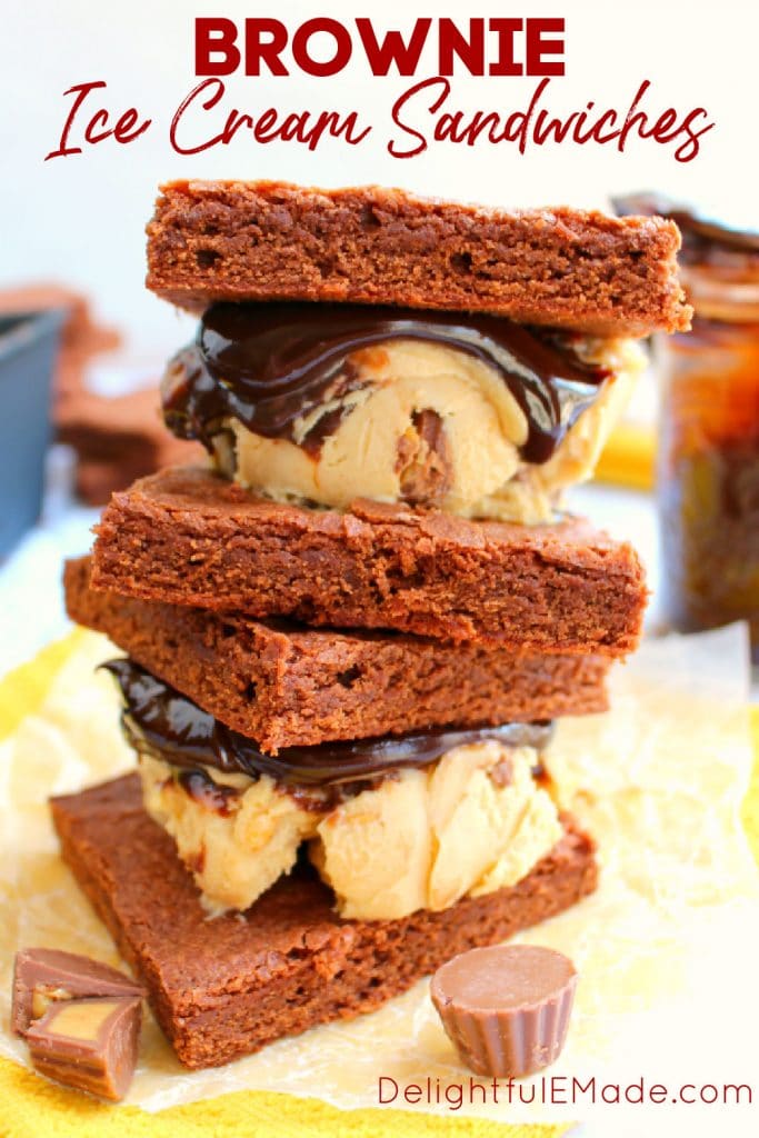 Two brownie ice cream sandwiches with hot fudge stacked on top of each other.