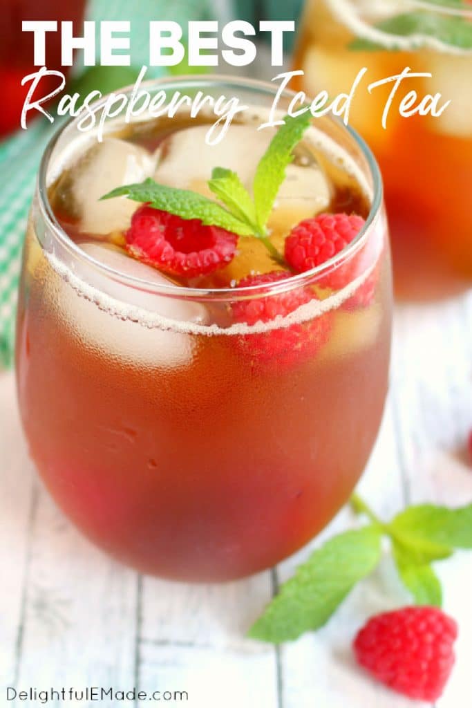 Glass of raspberry mint iced tea topped with fresh raspberries and mint sprig.