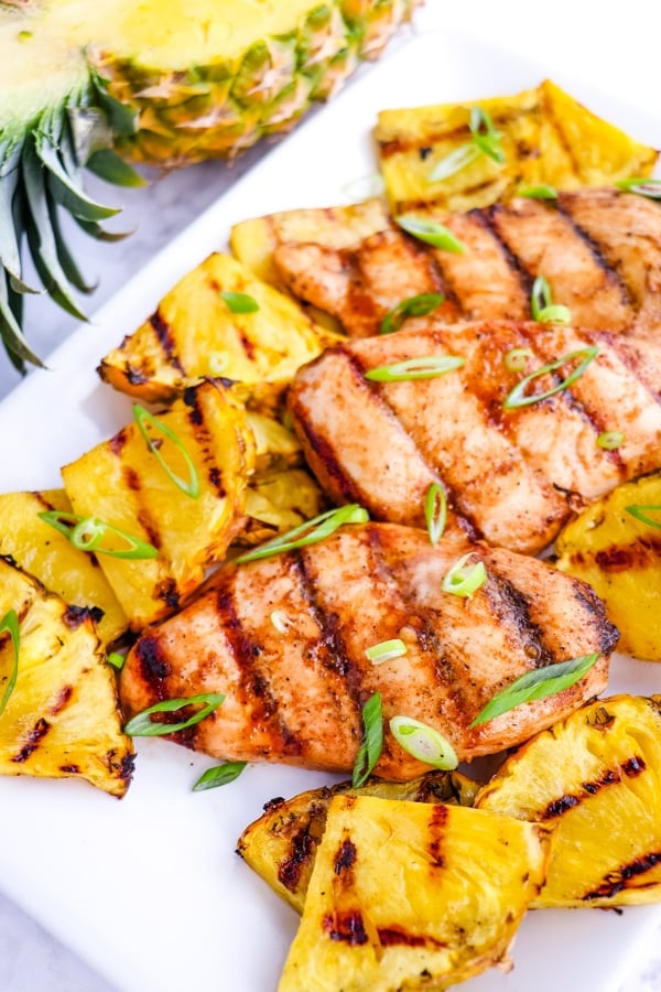 Pineapple grilled chicken on platter, garnished with sliced green onions.