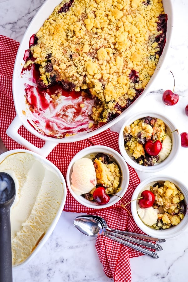 Cherry cobbler with cake mix served out of baking dish and into small bowls with ice cream.