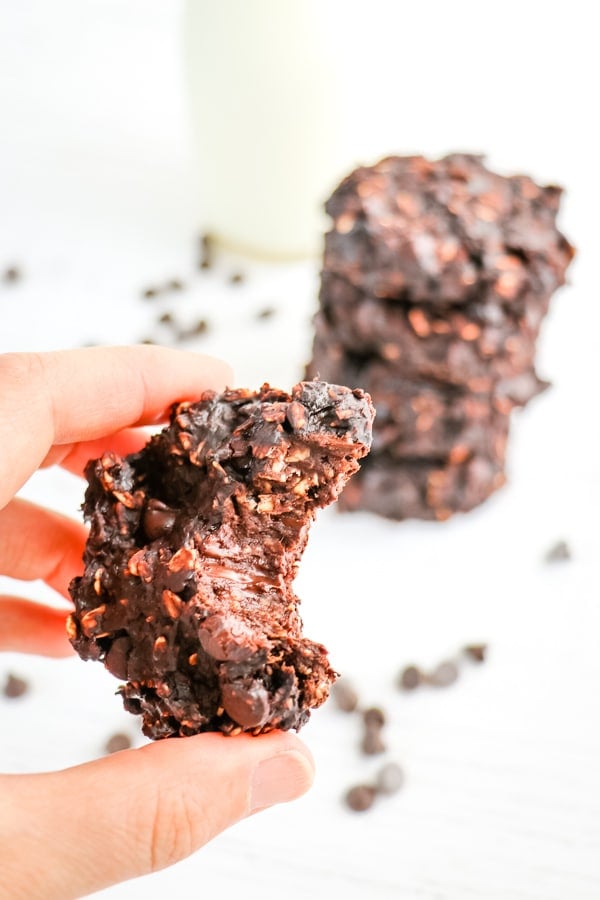 healthy chocolate oatmeal cookies, one cookie held with bite taken out.