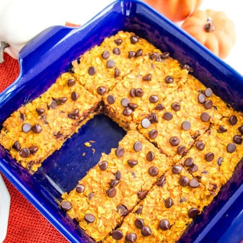 Pumpkin chocolate chip baked oatmeal cut into bars, with one bar missing in the baking dish.