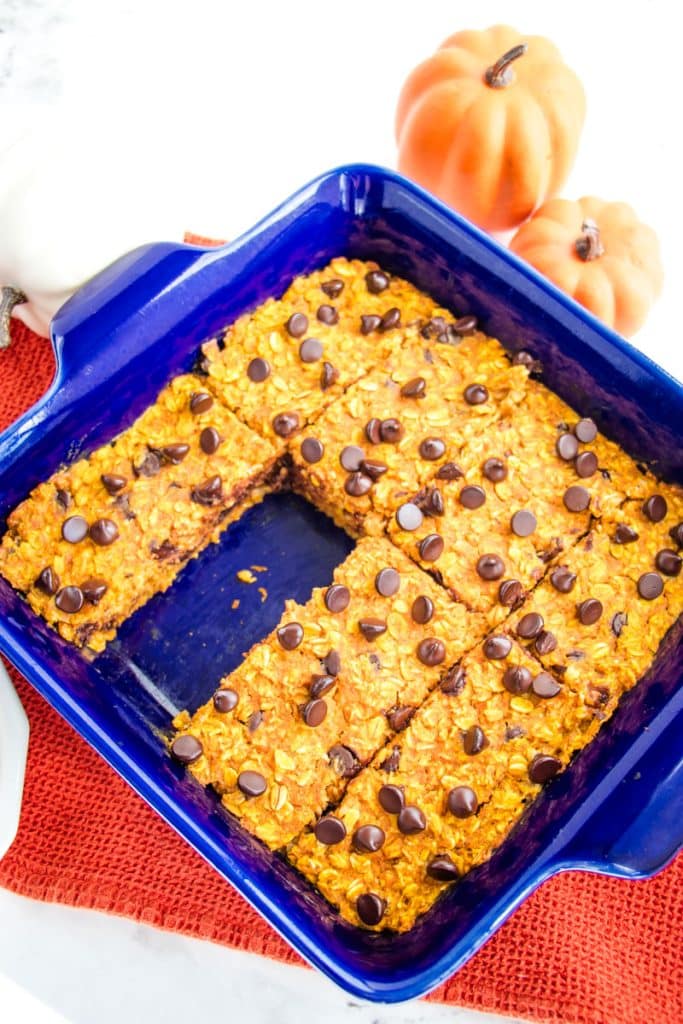 Pumpkin chocolate chip baked oatmeal cut into bars, with one bar missing in the baking dish.