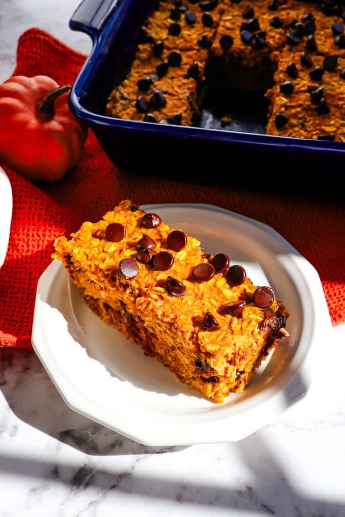 Pumpkin chocolate chip baked oatmeal bar on plate topped with chocolate chips.
