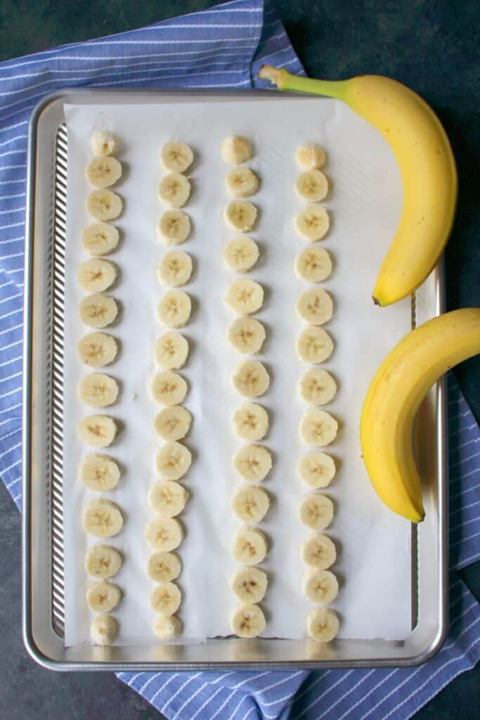 sliced bananas on sheet pan for freezing for peanut butter banana smoothie