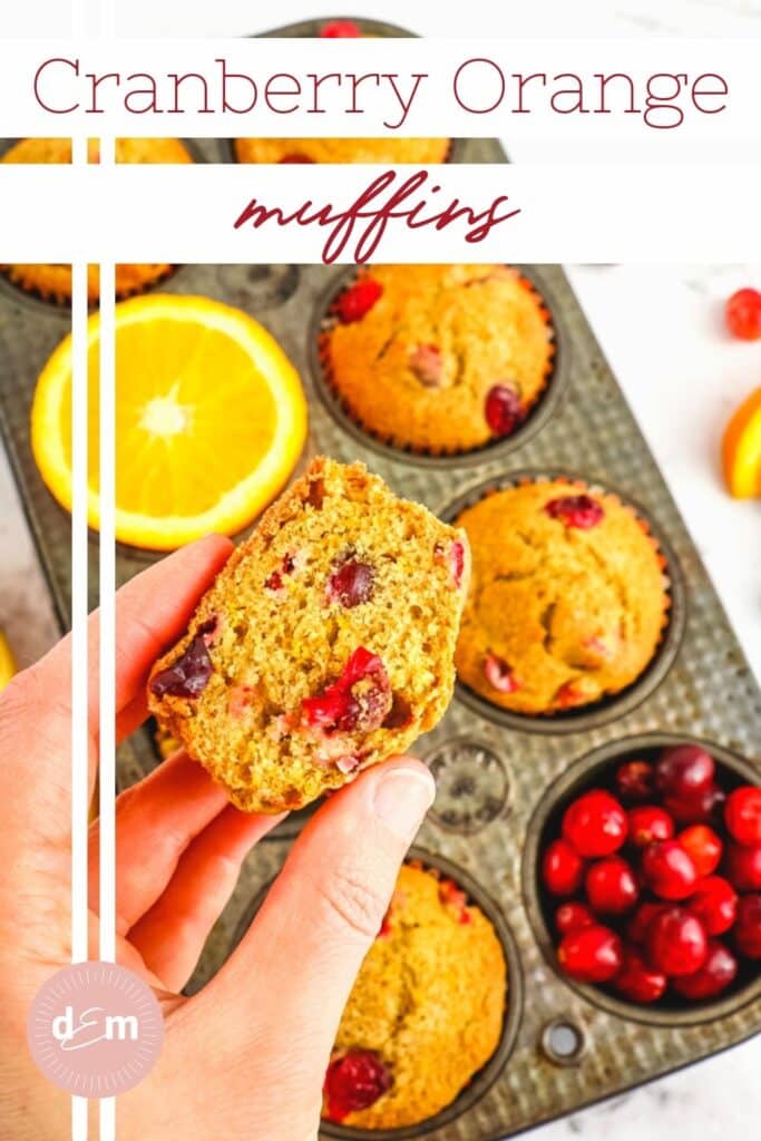 Half of a cranberry orange muffin held over a muffin tin.