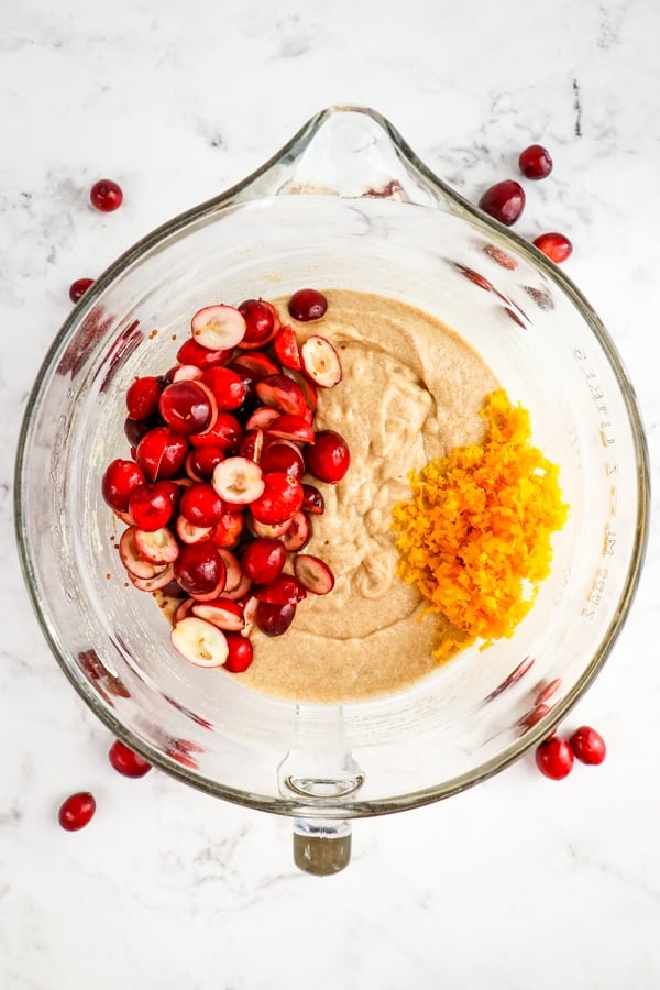 Wet and dry ingredients stirred together, with cranberries and orange zest on top.