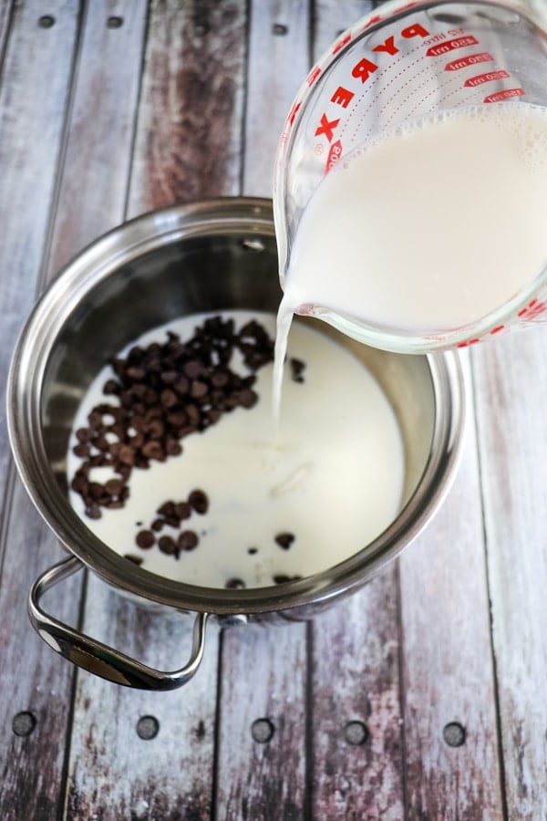 Pouring milk into saucepan to make homemade hot chocolate.