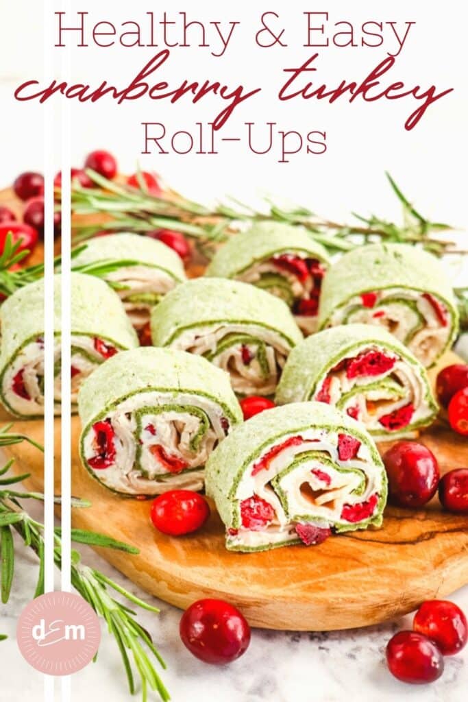 Cranberry turkey roll ups on a serving board garnished with cranberries.