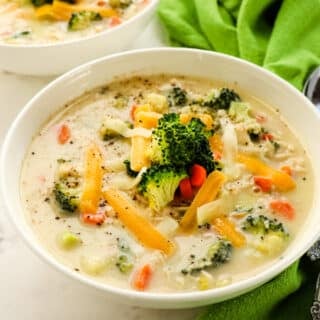 Bowl of healthy chicken broccoli cheese soup, with green napkin and spoons on the side.