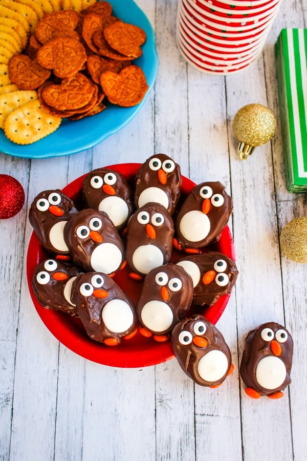 Plate of penguin cookies on table with other snacks.