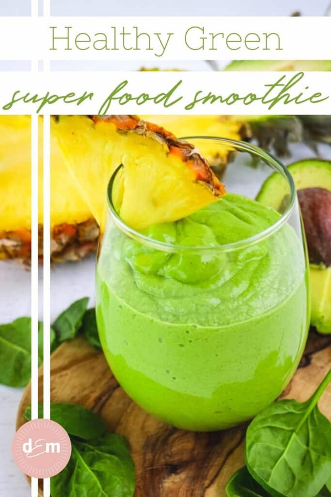 Green superfood smoothie in clear glass topped with pineapple slice.