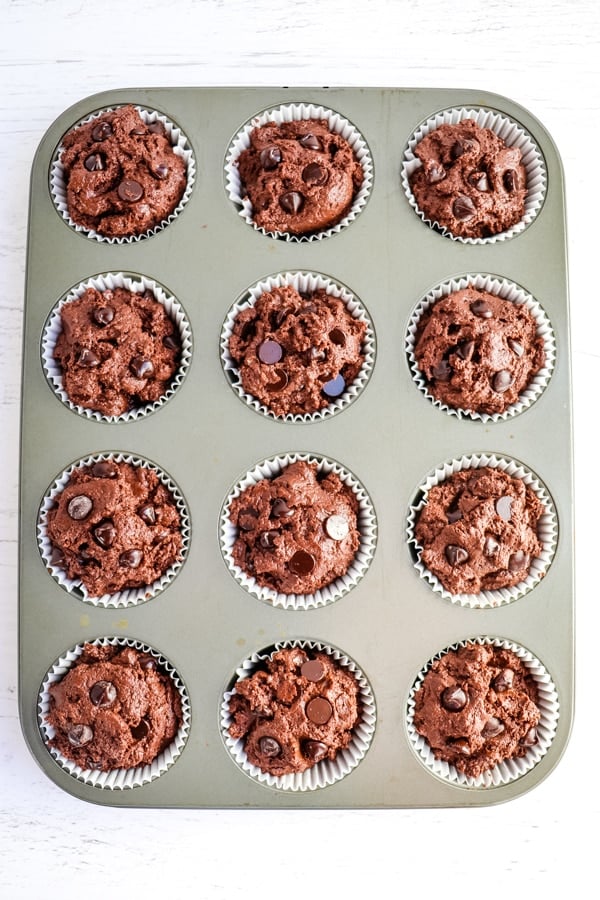 Double chocolate muffin batter in muffin tin, topped with chocolate chips, unbaked.