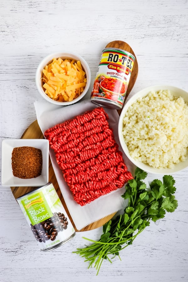 Ingredients needed to make one skillet Mexican beef and rice; cheese, ground beef, Rotel, cauliflower rice, taco seasoning and black beans.