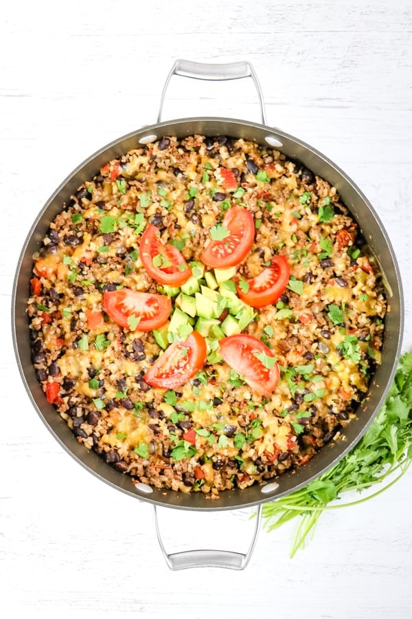 One skillet Mexican beef and rice topped with fresh tomato slices, cilantro and avocados.