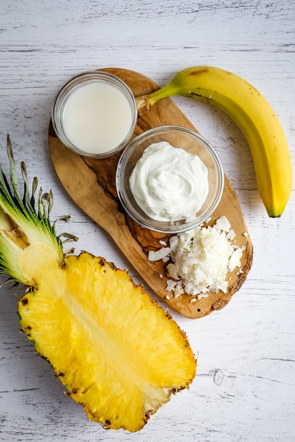 Ingredients for a pineapple coconut smoothie; pineapple, yogurt, almond milk and banana.