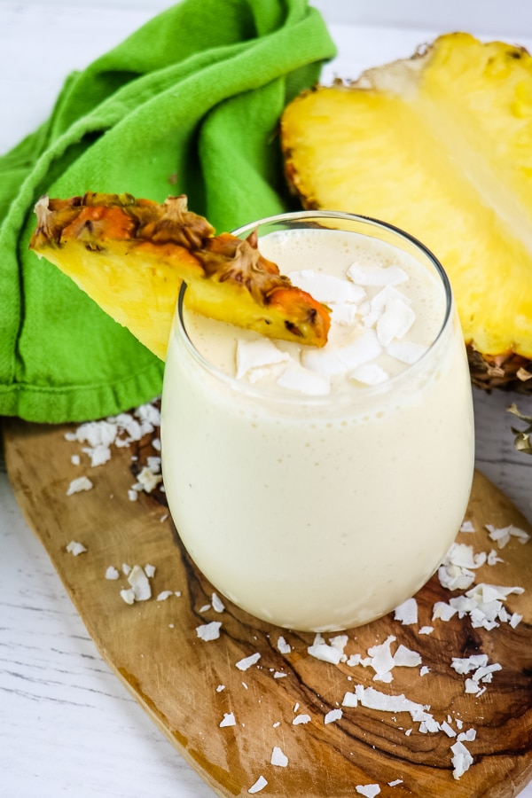 Pineapple coconut smoothie garnished with pineapple slice and coconut flakes.