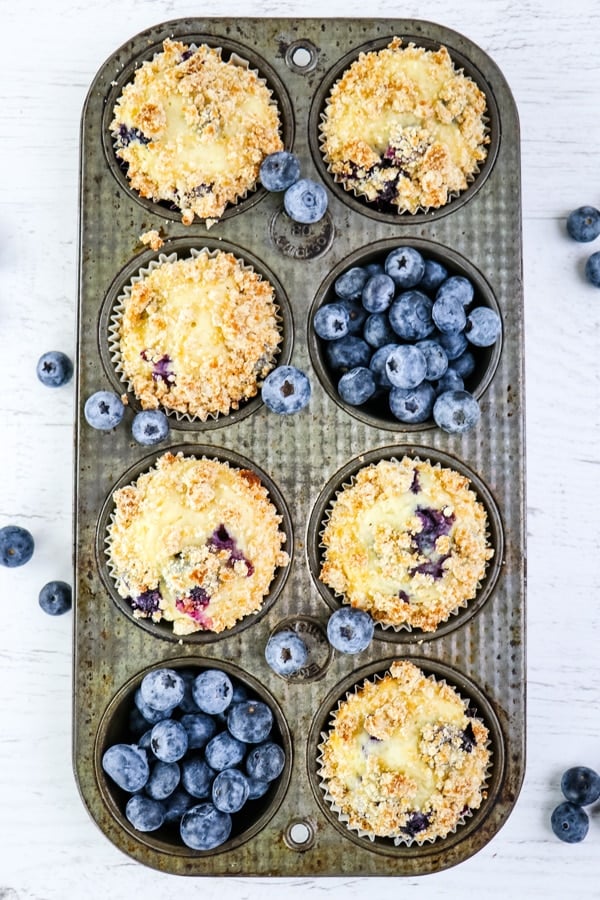 Healthy blueberry muffins in muffin tin with fresh blueberries.