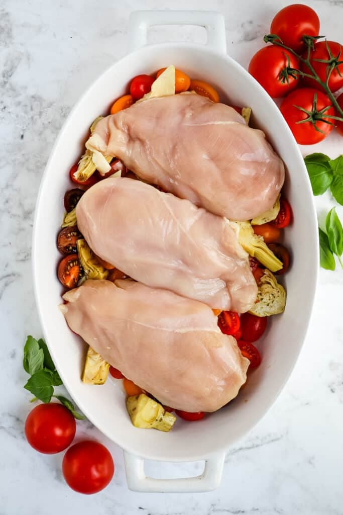 Chicken breasts placed on top of tomatoes for baked Italian chicken.