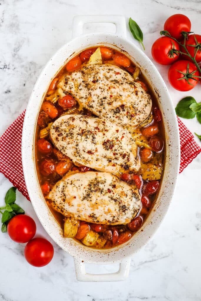 Baked chicken breasts in baking dish with cherry tomatoes.