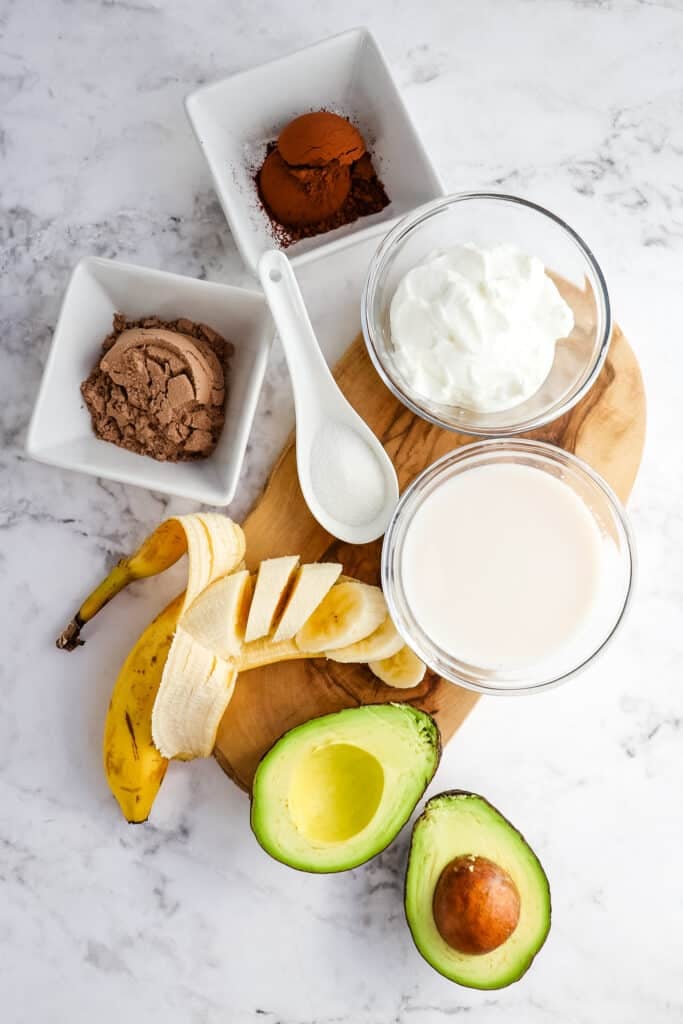 Ingredients needed to make a chocolate protein smoothie with avocado.