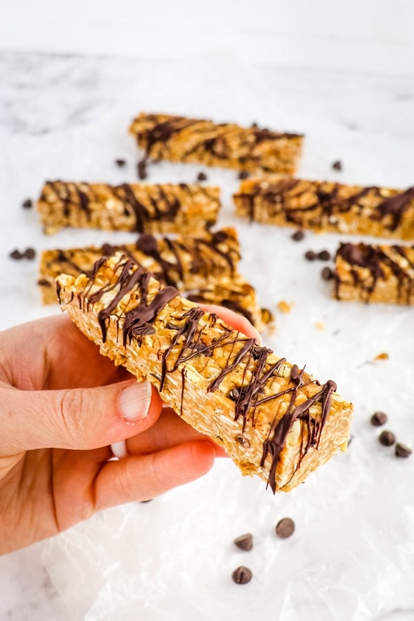 No bake granola bar drizzled with chocolate and held in hand.