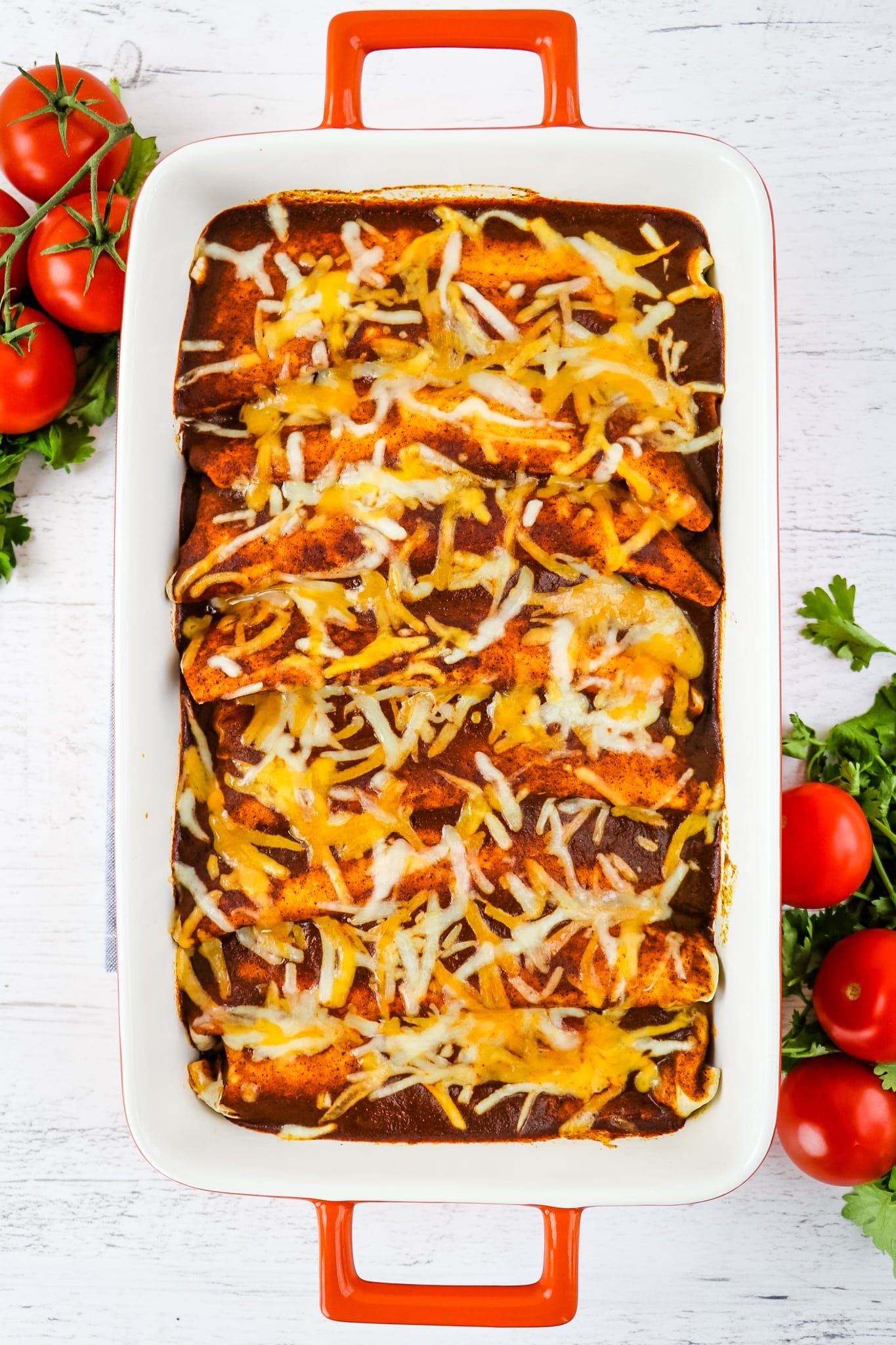 Pan of baked enchiladas with melted shredded cheese.