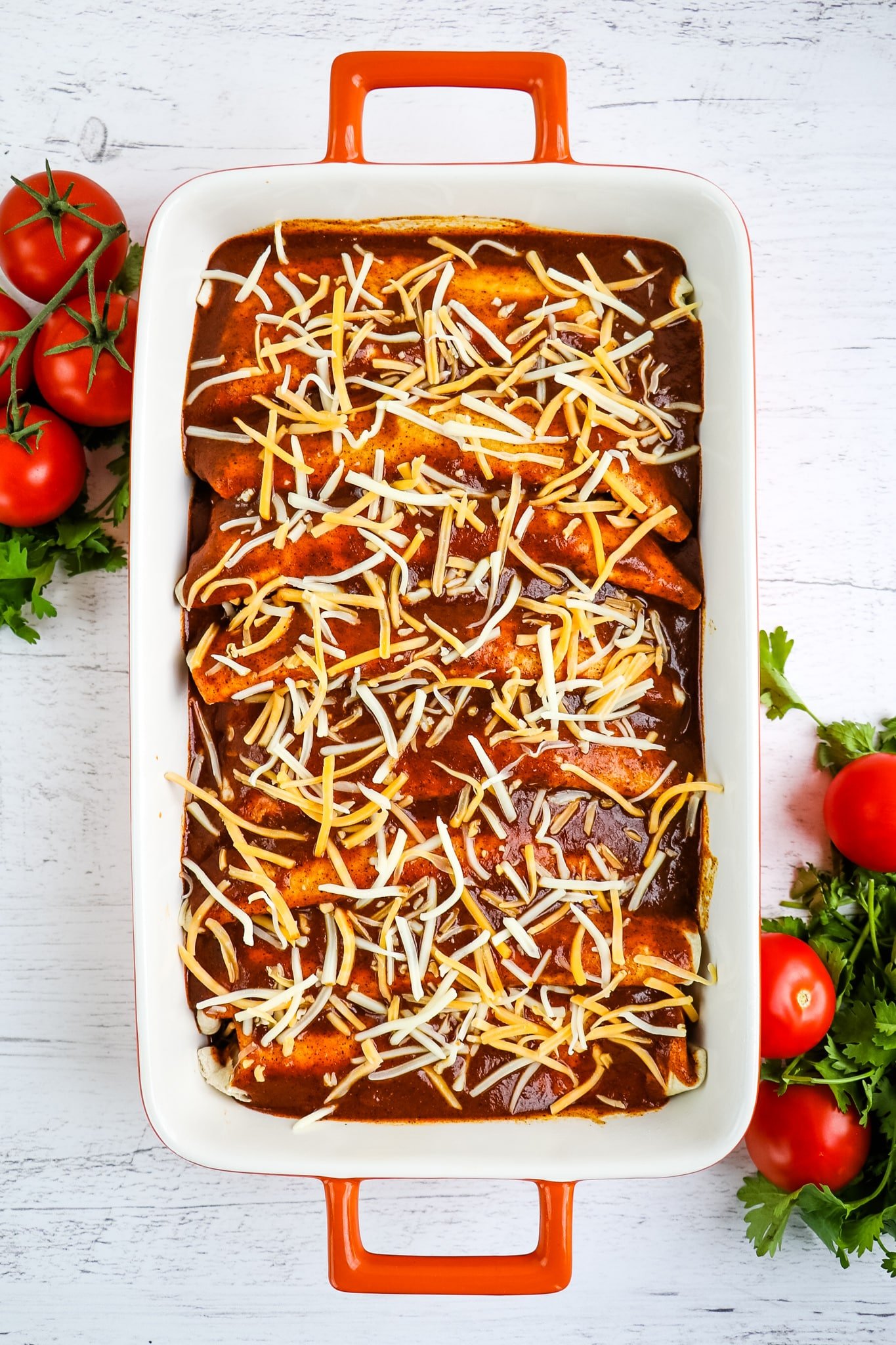 Enchiladas topped with enchilada red sauce and shredded cheese.