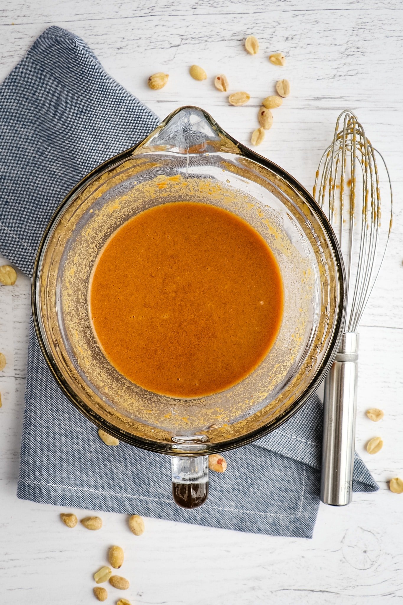 Peanut sauce in bowl with whisk on the side.