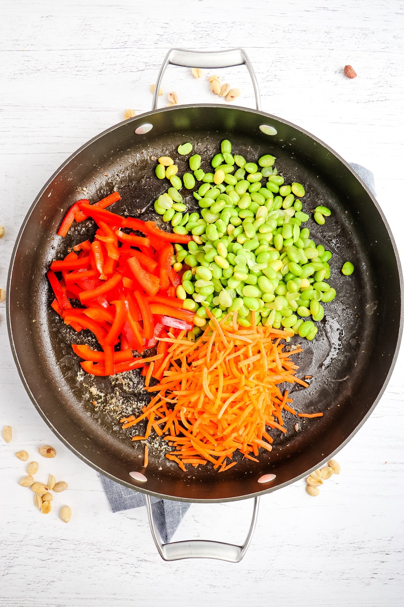 Shredded carrots, edamame and red peppers in skillet for stir fry.