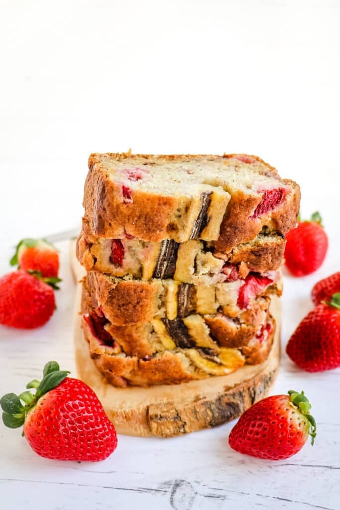 Stack of strawberry banana bread slices with whole fresh strawberries as garnishes.